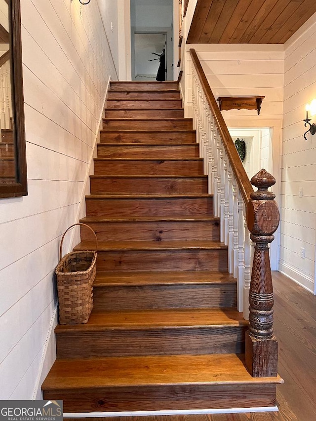 staircase featuring hardwood / wood-style floors, wood ceiling, and wooden walls