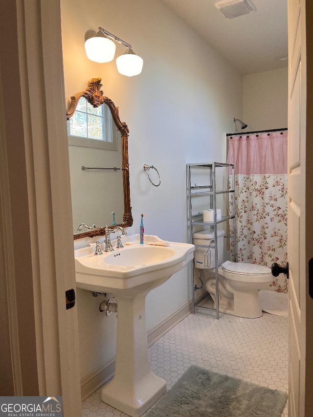 bathroom with tile patterned flooring, curtained shower, and toilet