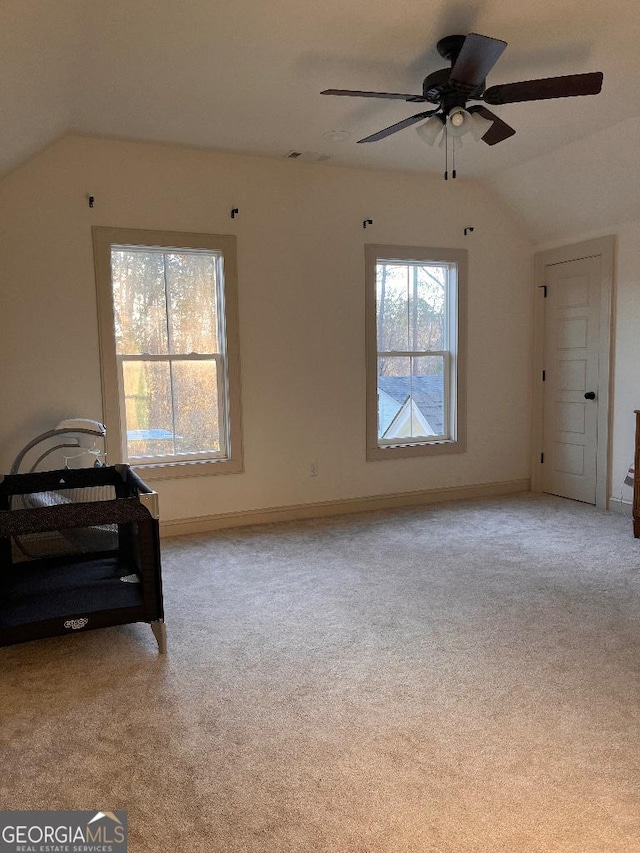 bedroom with multiple windows, lofted ceiling, and light carpet