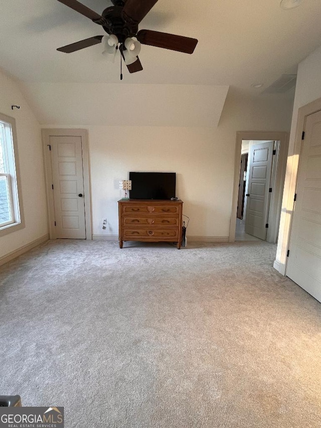 interior space featuring ceiling fan, vaulted ceiling, and light carpet