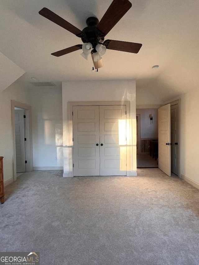 unfurnished bedroom featuring light carpet, a closet, and ceiling fan