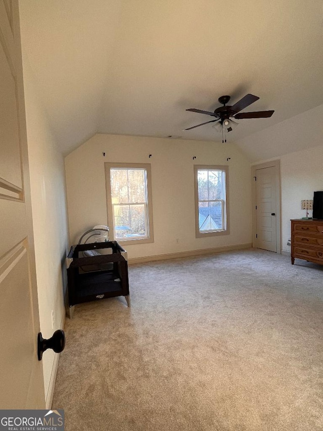 interior space featuring vaulted ceiling, light carpet, and ceiling fan