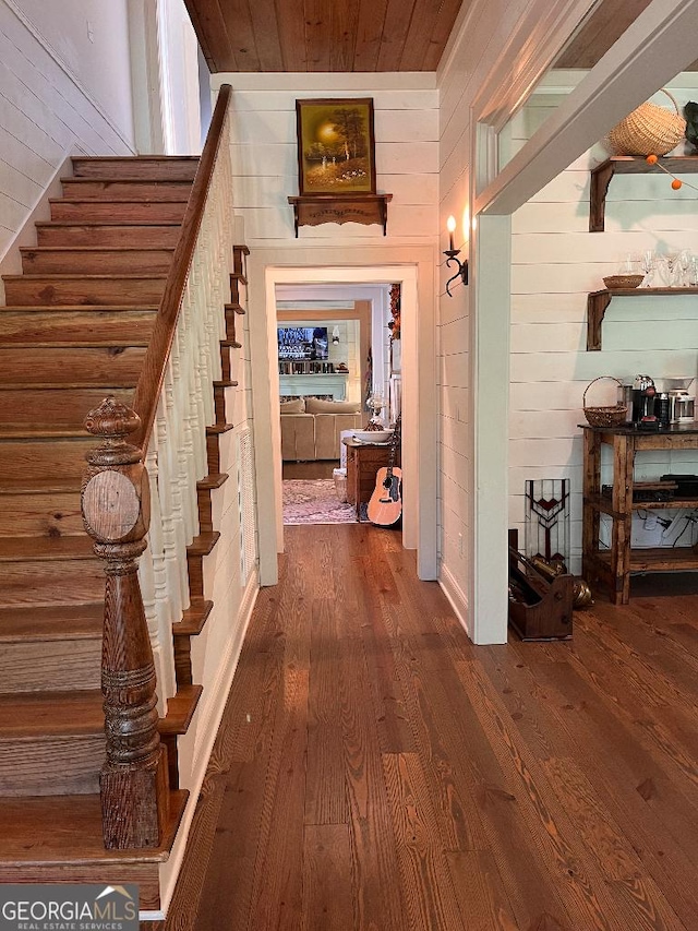 hallway featuring wooden walls, wood ceiling, and dark hardwood / wood-style flooring