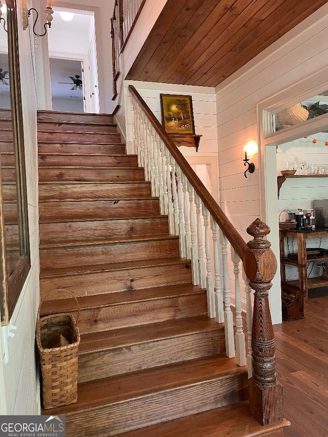 stairs featuring wood ceiling, ceiling fan, wood-type flooring, and wood walls