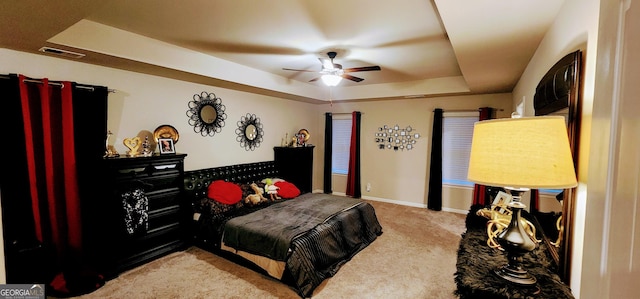 bedroom featuring a tray ceiling, light colored carpet, and ceiling fan