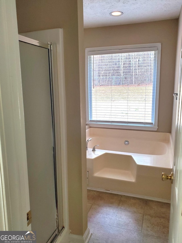 bathroom featuring a textured ceiling, tile patterned floors, shower with separate bathtub, and a healthy amount of sunlight