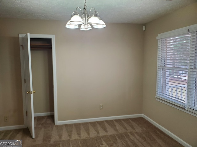 interior space with a notable chandelier, carpet flooring, a closet, and a textured ceiling