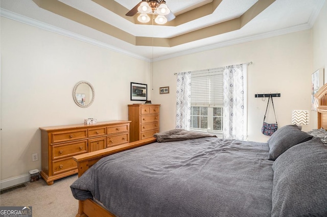 bedroom with crown molding, light colored carpet, a tray ceiling, and ceiling fan