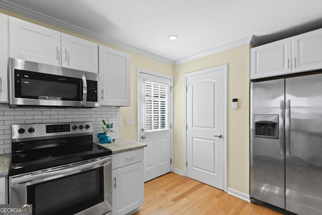 kitchen featuring ornamental molding, stainless steel appliances, light stone countertops, and white cabinets