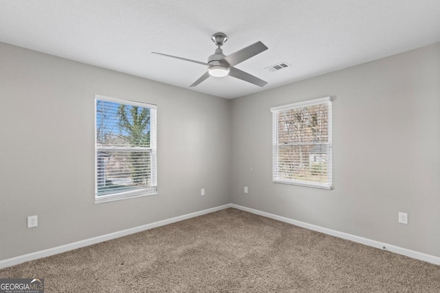 carpeted spare room featuring a wealth of natural light and ceiling fan