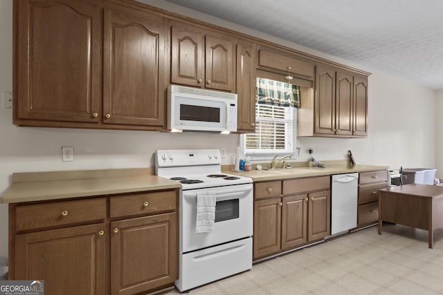 kitchen with white appliances, light floors, a sink, light countertops, and brown cabinets