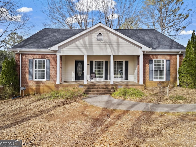 view of front of home with a porch, brick siding, and a shingled roof