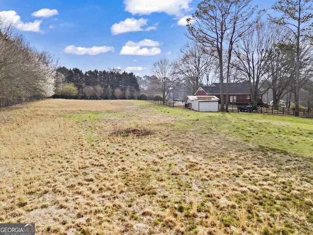 view of yard featuring fence, an outbuilding, a shed, and a rural view