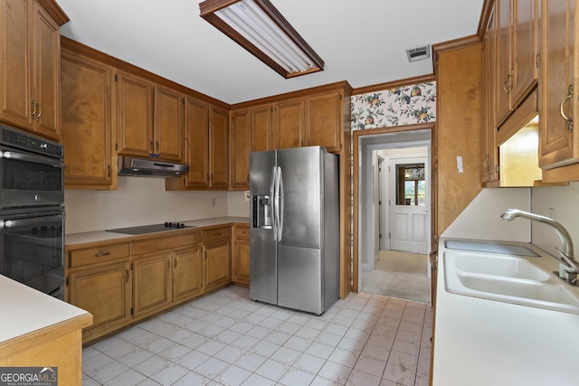 kitchen featuring visible vents, a sink, black appliances, light countertops, and under cabinet range hood