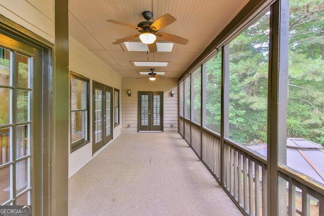 unfurnished sunroom with ceiling fan and a skylight