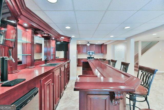 bar with sink, a paneled ceiling, and ceiling fan