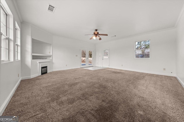 unfurnished living room featuring built in shelves, ceiling fan, ornamental molding, and carpet flooring