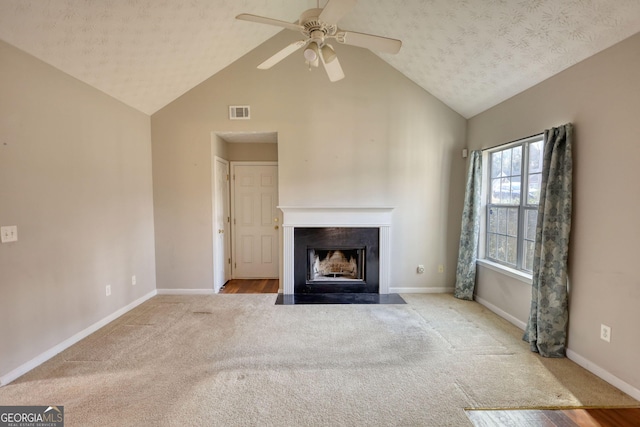 unfurnished living room featuring ceiling fan, lofted ceiling, light colored carpet, and a textured ceiling