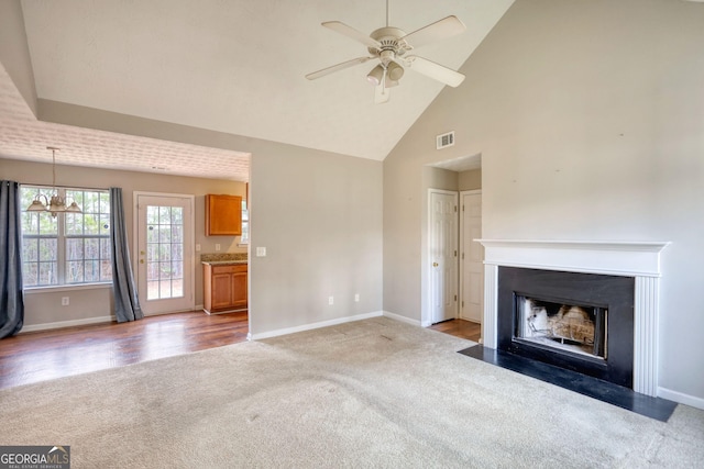 unfurnished living room with high vaulted ceiling, light carpet, and ceiling fan