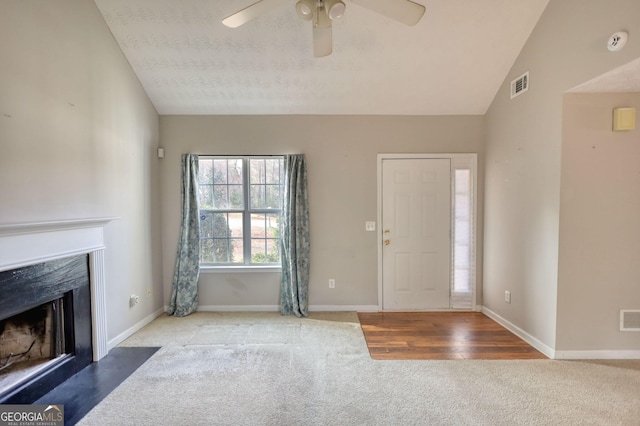 foyer entrance with lofted ceiling, a fireplace, carpet floors, and ceiling fan