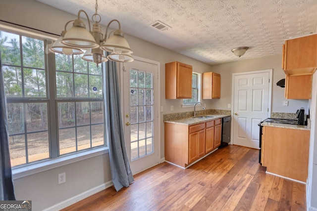 kitchen with sink, hardwood / wood-style flooring, an inviting chandelier, black dishwasher, and light stone counters