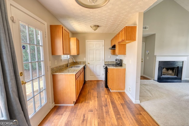 kitchen with sink, a high end fireplace, black electric range, a textured ceiling, and light wood-type flooring