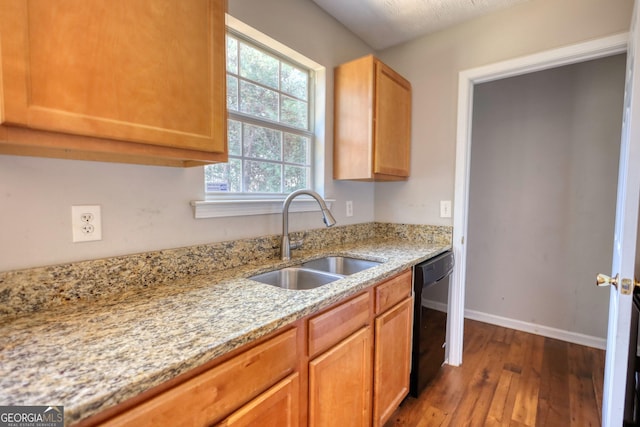 kitchen with sink, light stone countertops, dark hardwood / wood-style floors, and dishwasher