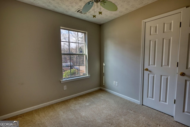 carpeted spare room featuring ceiling fan and a textured ceiling