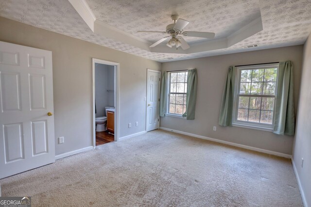 unfurnished bedroom featuring light carpet, crown molding, a raised ceiling, and a textured ceiling