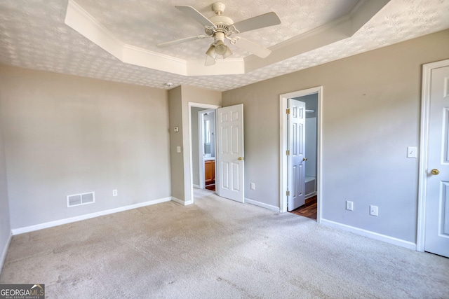 unfurnished bedroom featuring ceiling fan, carpet, ornamental molding, a textured ceiling, and a raised ceiling