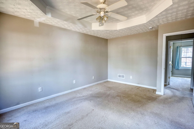 carpeted empty room featuring ceiling fan, ornamental molding, a raised ceiling, and a textured ceiling