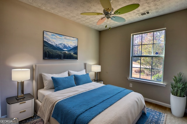 bedroom featuring multiple windows, ceiling fan, and a textured ceiling