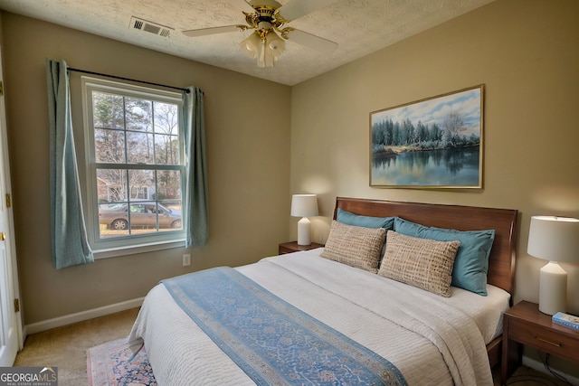 carpeted bedroom with ceiling fan and a textured ceiling