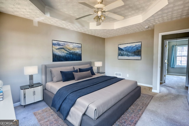 carpeted bedroom with ceiling fan, crown molding, a textured ceiling, and a tray ceiling