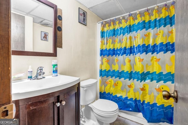 bathroom with a shower with curtain, a paneled ceiling, vanity, and toilet