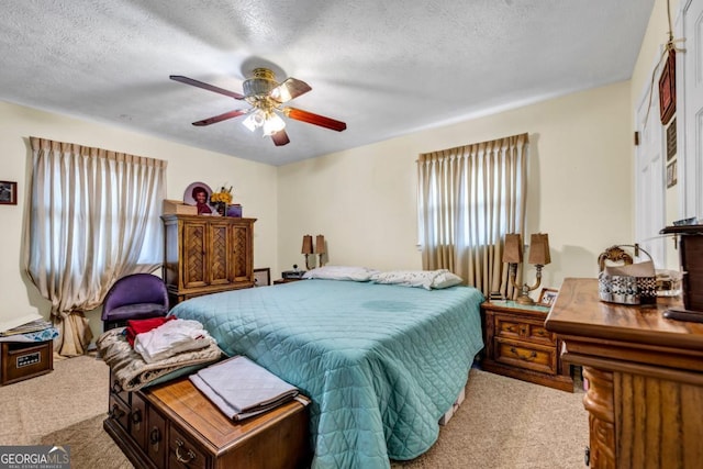 carpeted bedroom featuring ceiling fan and a textured ceiling