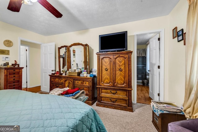 bedroom featuring light carpet, ceiling fan, and a textured ceiling