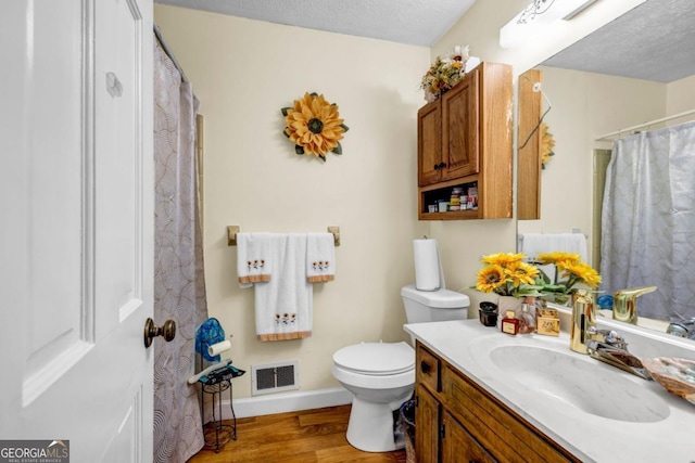 bathroom featuring vanity, toilet, hardwood / wood-style floors, and a textured ceiling