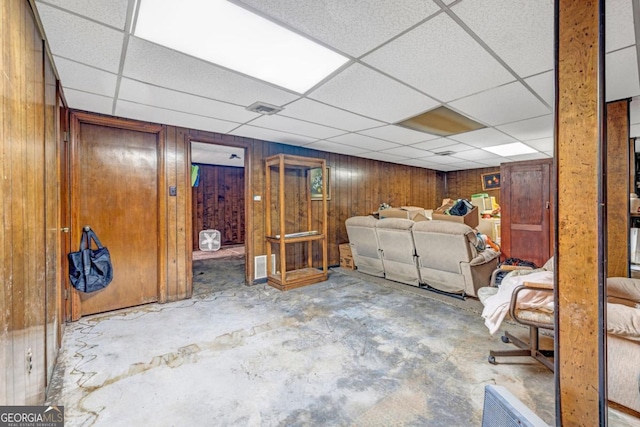 basement with a drop ceiling and wooden walls