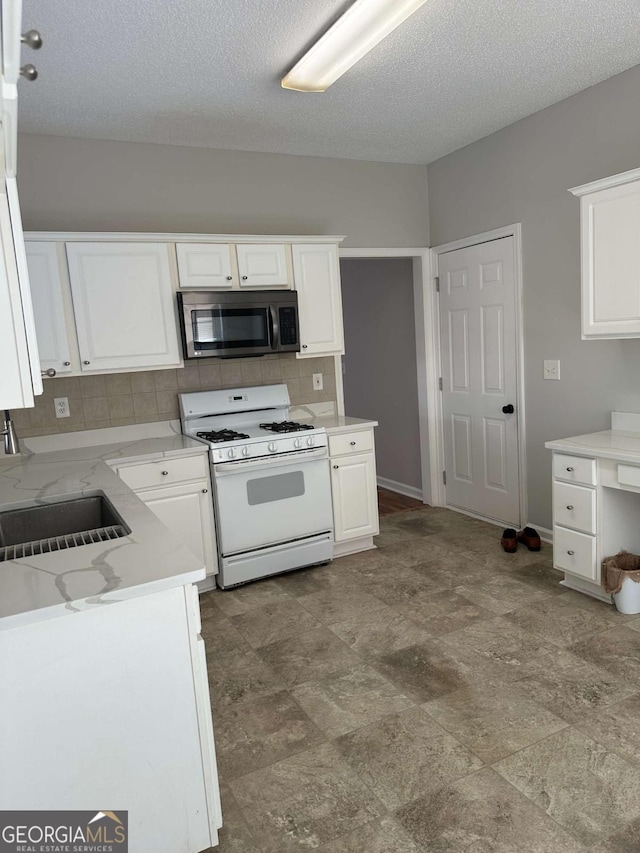 kitchen featuring sink, white cabinets, backsplash, gas range gas stove, and a textured ceiling