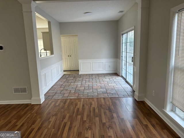 interior space with decorative columns, hardwood / wood-style floors, and a textured ceiling