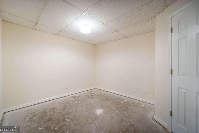 spare room with a paneled ceiling and concrete floors