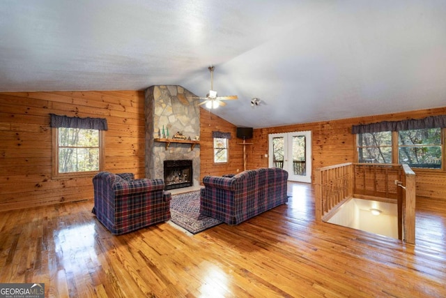 living room featuring wooden walls, lofted ceiling, wood-type flooring, and a fireplace