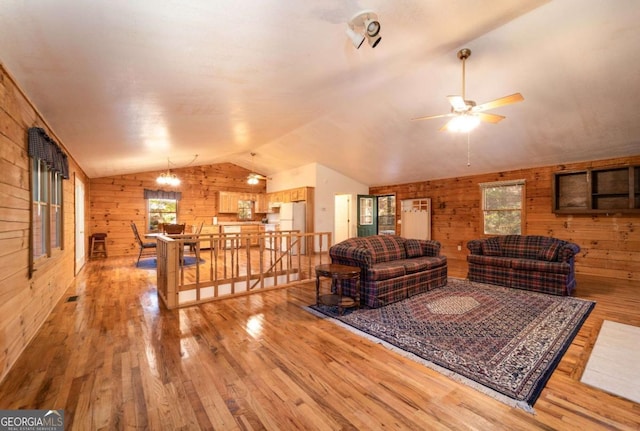 living room with hardwood / wood-style floors, vaulted ceiling, ceiling fan, and wood walls