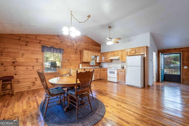 dining area with lofted ceiling, wooden walls, ceiling fan with notable chandelier, and light hardwood / wood-style floors