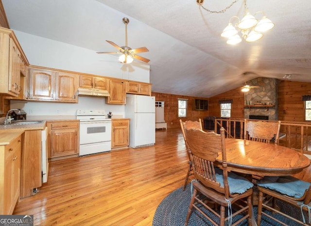 dining area featuring lofted ceiling, a stone fireplace, sink, light hardwood / wood-style flooring, and ceiling fan with notable chandelier