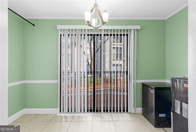 unfurnished dining area with tile patterned flooring, ornamental molding, and a chandelier