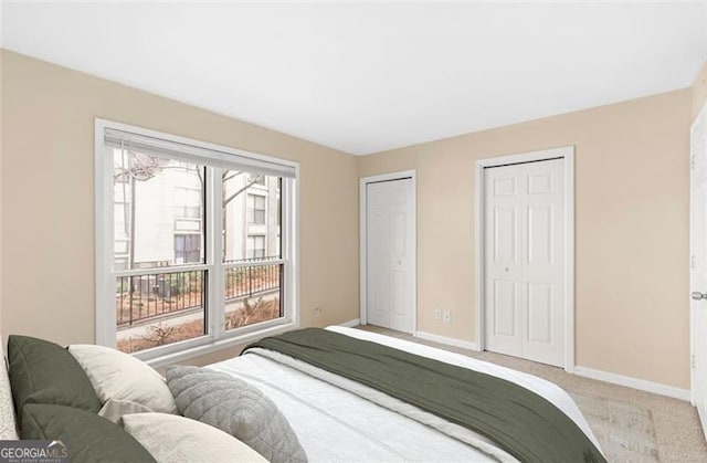 bedroom featuring light carpet and two closets