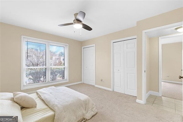 carpeted bedroom with ceiling fan and multiple closets