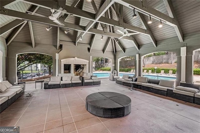 view of patio / terrace with an outdoor living space with a fireplace, a community pool, and ceiling fan